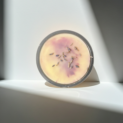 Round wax melt with dried herbs on a white surface