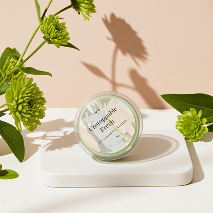 Jar of 'Unstoppable Fresh' product with green flowers on a beige background